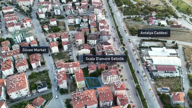 Kendi drone çekimine giydirilmiş mavi parsel sınırı ve yer etiketleri: şehir içinde apartmanlar arasındaki bir arsa